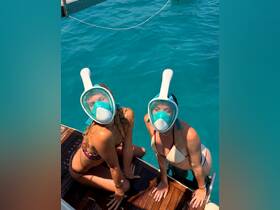 Two friends prepare for an exciting snorkeling adventure, showcasing the vibrant turquoise waters — perfect for underwater exploration and fun in the sun.