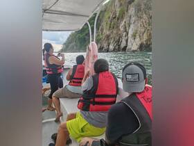 A group of tourists enjoys a scenic boat tour, capturing the stunning coastal views while wearing life jackets — a perfect adventure for nature lovers.