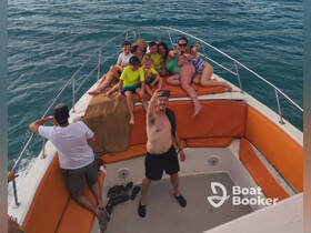 A joyful group of friends and family take a selfie on the deck of a boat, capturing a fun moment during their outing on the water.