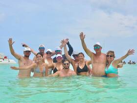 A lively group enjoys a fun day in the water, celebrating together in a beautiful beach setting — perfect for memorable outings and gatherings.