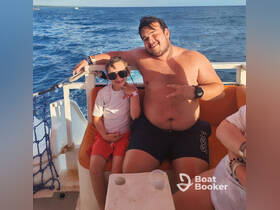 A joyful moment captured on a boat, featuring a young boy and an adult enjoying their time together on the ocean — perfect for family outings and adventures.