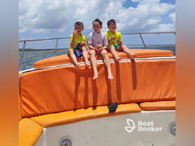 Three kids enjoy snacks while sitting on the bow of a boat, capturing a fun moment on the water — perfect for family outings and adventures.
