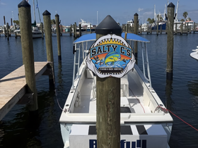 A clear view of the 'Salty C's' boat docked at the marina, showcasing its name and structure against a backdrop of calm waters and other vessels.