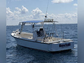 A sleek center console boat named 'Boxfull' is anchored in calm waters, showcasing its fishing gear and spacious design, perfect for a day on the water.