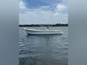 A pristine center console boat anchored in calm waters, showcasing its sleek design against a backdrop of blue skies and greenery.
