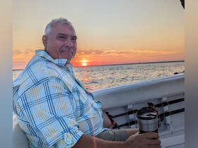 A man enjoys a serene sunset on a boat, capturing the perfect moment of relaxation on the water.