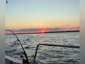 A serene sunset view from a fishing boat, showcasing the tranquil waters and vibrant colors of the sky — perfect for evening fishing trips.