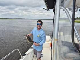 A man proudly displays his catch while fishing from a boat, showcasing the thrill of a successful day on the water.