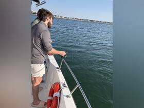 Two friends enjoy a fishing trip on a boat, casting their lines into the sparkling water — a perfect day for angling and camaraderie.