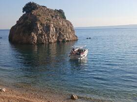 A group enjoys a scenic boat ride near a rocky island, perfect for exploring the beautiful coastline and swimming in crystal-clear waters.