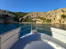 A serene view from the bow of a boat, showcasing the tranquil waters and scenic cliffs of a secluded bay — perfect for peaceful getaways.