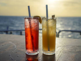 Two refreshing cocktails sit on a table with a stunning ocean backdrop, perfect for enjoying a relaxing day on the water.