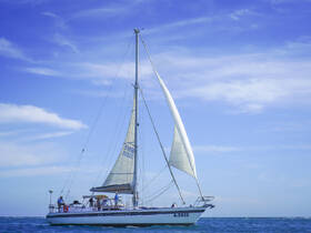 A lively group enjoys sailing on a beautiful day aboard a sleek sailboat, navigating the sparkling ocean waters.