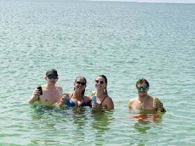 A group of friends enjoys a refreshing day in the water, holding drinks and soaking up the sun — the perfect beach party vibe.