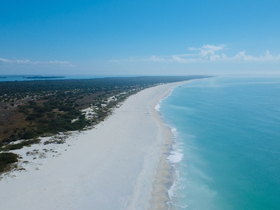 A stunning aerial view of a pristine beach coastline, showcasing the beautiful contrast between the white sands and turquoise waters — perfect for beach lovers and nature enthusiasts.