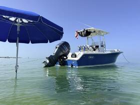 A sleek speedboat anchored in calm waters, complemented by a blue umbrella for shade — perfect for a relaxing day on the water.