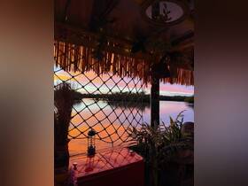 A cozy interior view of a boat with a stunning sunset reflected on the water, showcasing decorative elements and a serene atmosphere perfect for relaxation.