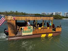 A lively group enjoys a tiki boat experience in Naples, showcasing a fun atmosphere on the water with vibrant decorations and a welcoming vibe.