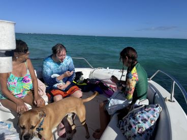 A joyful group enjoys time on a boat, with a dog joining the fun — a perfect family outing on the water.