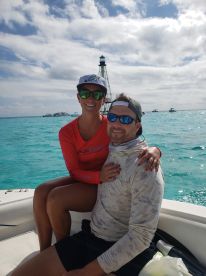 A happy couple enjoys a moment on a boat with a scenic lighthouse in the background, perfect for romantic getaways and ocean adventures.