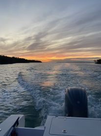 A stunning sunset view from the back of a boat, showcasing the tranquil waters and vibrant sky, perfect for evening cruises.