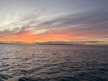 A breathtaking sunset over the tranquil waters, showcasing vibrant colors and a serene coastline — perfect for romantic evenings or peaceful getaways.