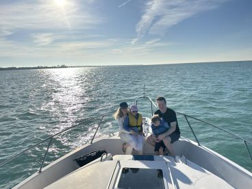 A joyful family enjoys a sunny day on a boat, creating lasting memories on the water with the ocean sparkling in the background.