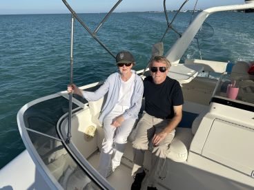 A couple relaxes on the deck of a boat, enjoying the beautiful ocean view — perfect for a romantic getaway or a day on the water.