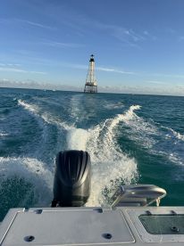 A scenic view of a lighthouse in the distance as the boat speeds through turquoise waters, capturing the essence of a perfect day on the ocean.