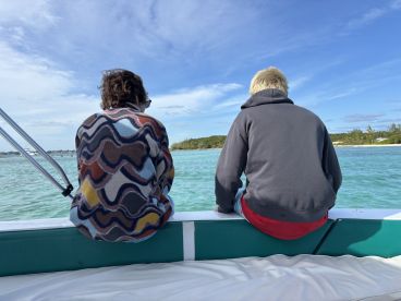 Two young individuals enjoy the serene ocean view from the boat, capturing a moment of relaxation and adventure on the water.