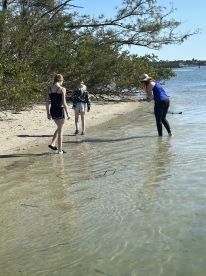 A group of individuals, including children, explore a sandy beach, enjoying a day of adventure by the water — perfect for family outings and nature exploration.