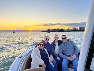 A group of friends enjoys a beautiful sunset on the water, capturing a perfect moment of camaraderie and relaxation aboard their boat.