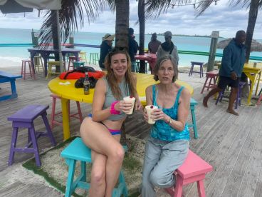 Two women enjoy refreshing cocktails at a colorful beachside bar, capturing the essence of a fun day in paradise.