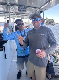 Two friends enjoy a fun moment aboard a boat, showcasing camaraderie and celebration with drinks in hand — perfect for a day out on the water.