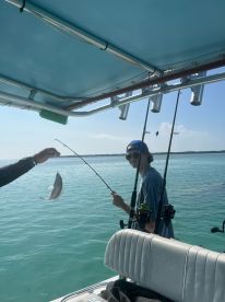 A young angler smiles while reeling in a catch during a fishing trip, showcasing the excitement of on-water activities.