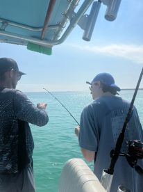 Two individuals enjoy a fishing trip on a boat, showcasing the excitement of angling in the open ocean — a perfect bonding experience on the water.
