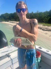 A young man proudly displays his catch while fishing from a boat, showcasing the excitement of a day on the water.