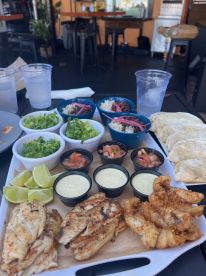 A delicious spread of grilled fish, tacos, and fresh sides, perfect for enjoying a meal on board or at a waterfront restaurant.
