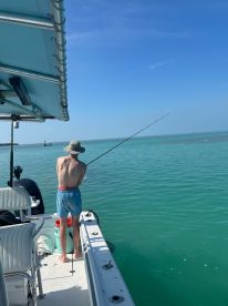 A young boy enjoys fishing from the deck of a boat in clear blue waters, capturing the essence of a perfect day on the water.