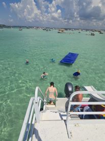 A lively scene at a sandbar where guests enjoy swimming and fun activities off a pontoon boat, showcasing the perfect day on the water.