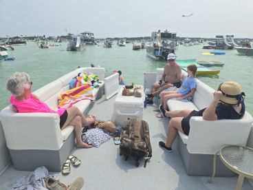A family enjoys a relaxing day on a pontoon boat, surrounded by other vessels in the water — perfect for summer outings and family gatherings.