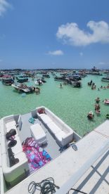 A vibrant scene at a sandbar with numerous boats and people enjoying the clear waters, perfect for a lively day of swimming and relaxation.