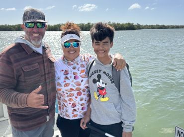 A joyful family poses for a photo on a fishing trip, showcasing the fun and adventure of spending time together on the water.