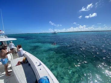 Guests enjoy a fun day on the water, swimming in the crystal-clear turquoise waters while anchored near a beautiful coastline — perfect for group adventures and aquatic activities.