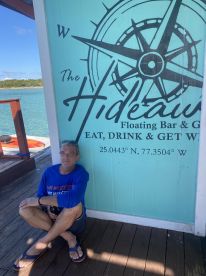 A guest relaxes at The Hideout Floating Bar & Grill, enjoying the scenic waterfront view — a perfect spot for drinks and relaxation in the Bahamas.
