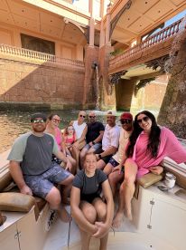 A cheerful group of friends and family enjoy their time aboard a boat, surrounded by stunning architecture and waterfalls — perfect for memorable outings and celebrations.