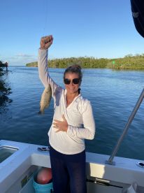 A woman proudly displays her catch while fishing from a boat, showcasing the excitement of a successful day on the water.
