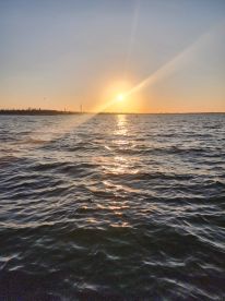 A serene sunset over the water, capturing the tranquil beauty of the coastline — perfect for evening boat cruises.