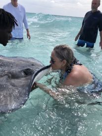 A woman shares a close encounter with a stingray in shallow waters, showcasing an unforgettable wildlife experience in the ocean.