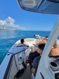 A group enjoys a relaxing day on the water aboard a boat, with scenic views of the coastline and clear blue skies.